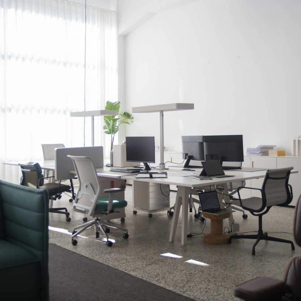 A spacious office interior in Portugal with desks, chairs, and computers under natural light.